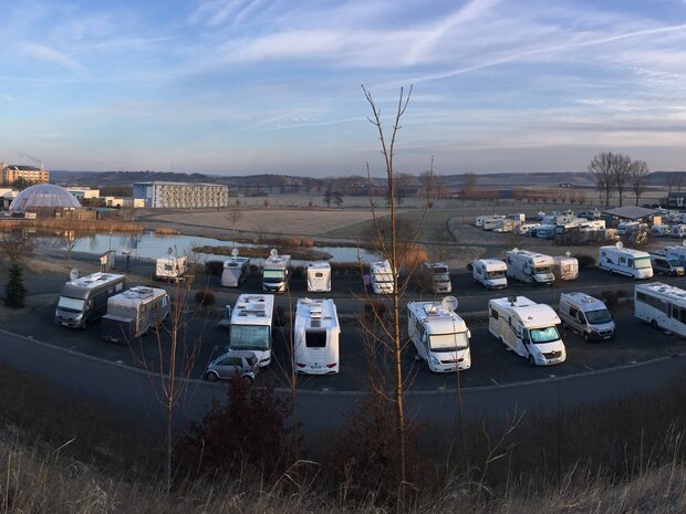 Großer Stellplatz mit vielen Reisemobilen in Reihen.