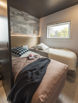 Kleines Schlafzimmer mit zwei Einzelbetten in L‑Form.