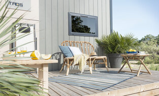Kleine Terrasse mit Sitzbank, Pflanzen und Beistelltischen.