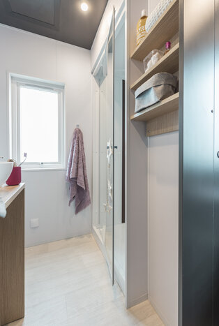 Modernes Badezimmer mit Glasdusche, Holzregalen und Fenster.